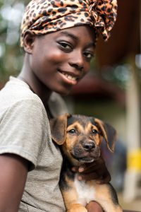 girl in rural Panama helping a little puppy dog