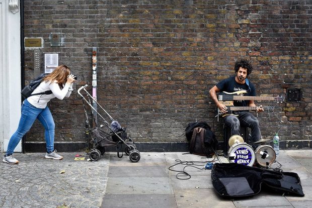 student on the street photography course taking pictures of a musician in central London student on the street photography course taking pictures of a musician in central London